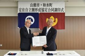 中嶋山鹿市長と高巣和水町長が協定を結んでいる写真