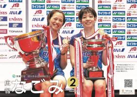 第74回全日本総合バドミントン選手権大会の女子ダブルスで優勝した福島由紀選手と廣田彩花選手が、優勝カップと金メダルを手に持って微笑んでいる写真